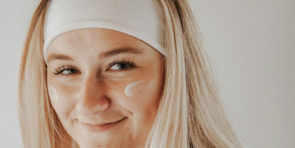 woman applying moisturiser on face after spray tan